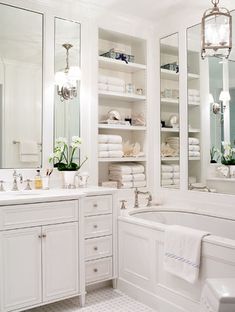 a large bathroom with white fixtures and lots of towels on the shelf above the bathtub