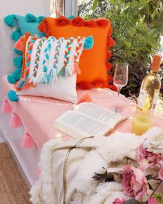 a bed topped with pillows next to a bottle of wine and a vase filled with flowers