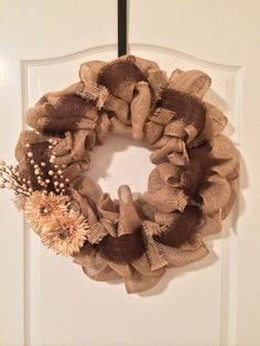 a burlap wreath hanging on a door with flowers in the center and an antler