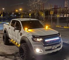 a white pickup truck parked in a parking lot at night with its lights turned on