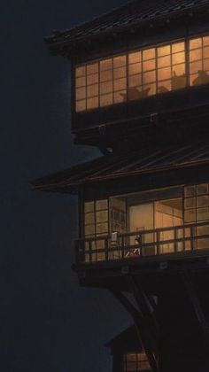 two people are standing on the balcony of a building at night with their windows lit up