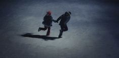 two people walking in the snow at night with one holding the other's hand