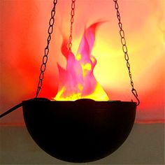 a fire pit with chains hanging from it's sides and the flames glowing brightly in the background