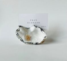 an oyster shell with a business card in the middle on a white tablecloth background