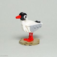 a lego duck sitting on top of a piece of wood next to a white wall