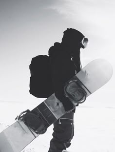 a snowboarder is carrying his board in the snow