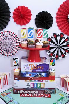 a table topped with cupcakes and paper fans next to a board game tray