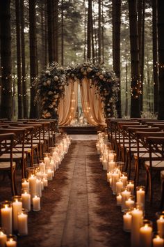 an outdoor wedding setup with candles and flowers on the aisle, surrounded by tall trees