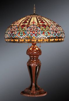 a lamp that is sitting on top of a wooden stand with a stained glass shade