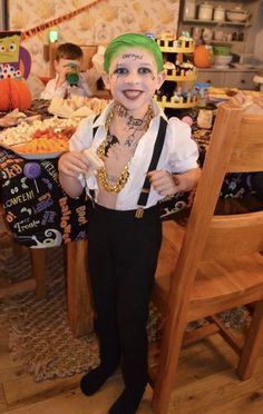 a young boy dressed up as a clown with green hair and tattoos on his face