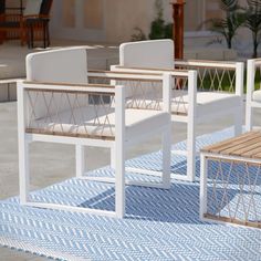 two white chairs sitting on top of a blue rug next to a bench and table