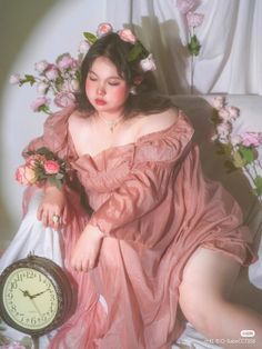 a woman in a pink dress sitting on a chair with a clock next to her