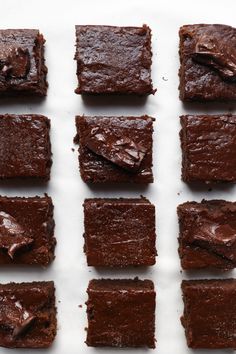 nine pieces of brownie sitting on top of a white table next to each other