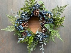 a wreath with pine cones and blue berries