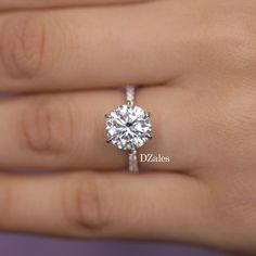 a woman's hand with a diamond ring on top of her finger, showing the center stone