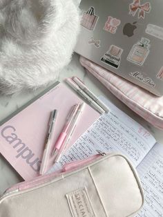 a pink case sitting on top of a counter next to a pen and notebooks