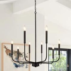 a black chandelier hanging from the ceiling in a dining room with white walls