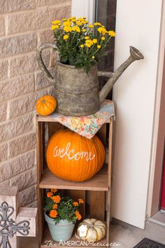 pumpkins, flowers and watering can are sitting on a shelf in front of the door