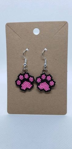 a pair of pink and black beaded earrings with an animal paw print on it