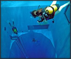 two people in scuba gear are diving into a blue swimming pool with the words nemo 33 above them