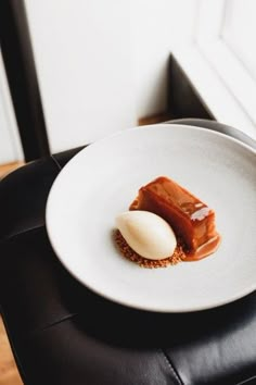 a white plate topped with food on top of a black leather chair next to a window