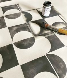 a black and white checkered floor with a paintbrush next to it on the floor