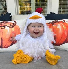 a baby in a chicken costume sitting on a couch