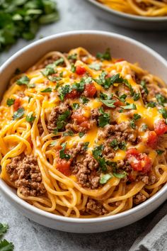 a white bowl filled with spaghetti topped with ground beef and cheese, garnished with parsley