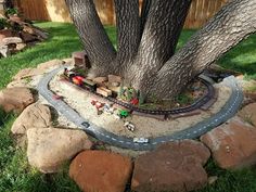 a toy train set sitting under a tree