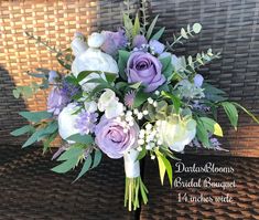 a bridal bouquet with purple flowers and greenery on a wicker tablecloth