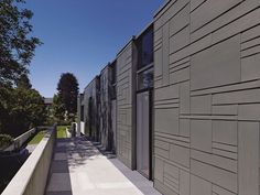 an exterior view of a building with grey sidings and trees on the other side