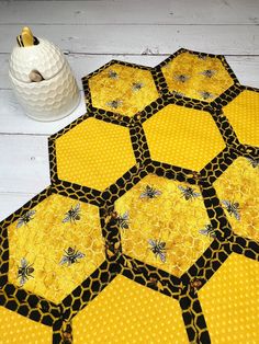 yellow and black hexagons with bees on them sitting next to a white vase