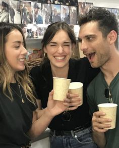 two women and a man holding coffee cups