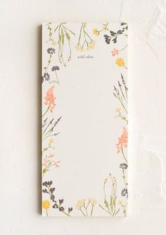 a notepad with flowers on it sitting on top of a white table next to a wall