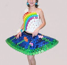 a woman in a dress made out of bottle caps is posing with her hands on her hips