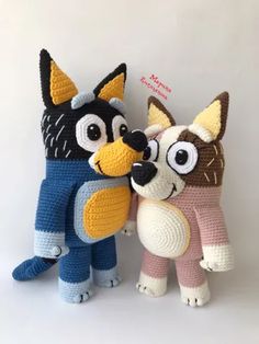 two crocheted stuffed animals standing next to each other on a white background with the caption cat and dog