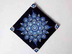 a blue and black square with an intricate design on the center is sitting on a white surface