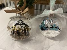 two christmas ornaments with the words believe and an ornament hanging from a ribbon