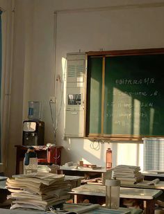 an empty classroom with many books on the desk and a chalkboard in the background