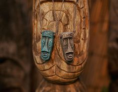 two carved wooden faces are hanging from the side of a carvingd wood statue,