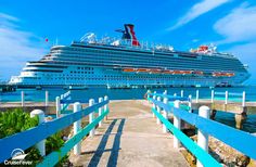 a large cruise ship docked at a pier in the ocean with blue skies and clouds