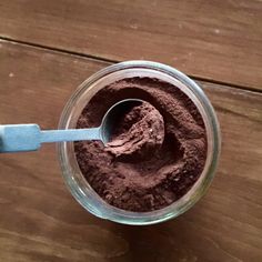 a spoon is in a cup with some chocolate powder on the table next to it