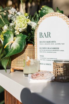 a bar sign sitting on top of a table next to a vase filled with flowers