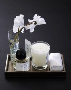 a candle and some other items on a tray with a flower in the vase next to it