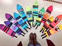 a person's feet standing in front of colorful paper puppets