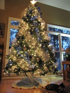 a white christmas tree with clear lights in a living room next to a large window