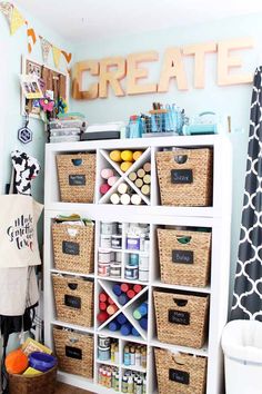 a white shelf filled with lots of crafting supplies next to a black and white curtain