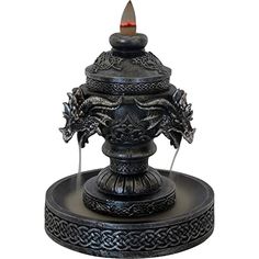 an ornate metal fountain with a red light in the center and two dragon heads on top