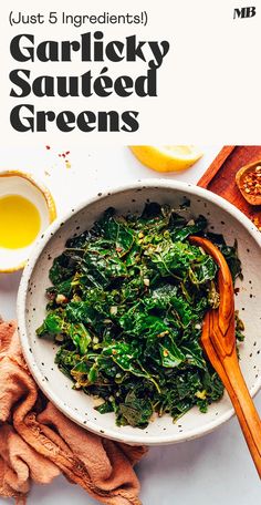 a white bowl filled with greens next to sliced oranges and other ingredients on a table