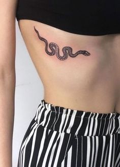 a woman's stomach with a snake tattoo on her left side ribcage